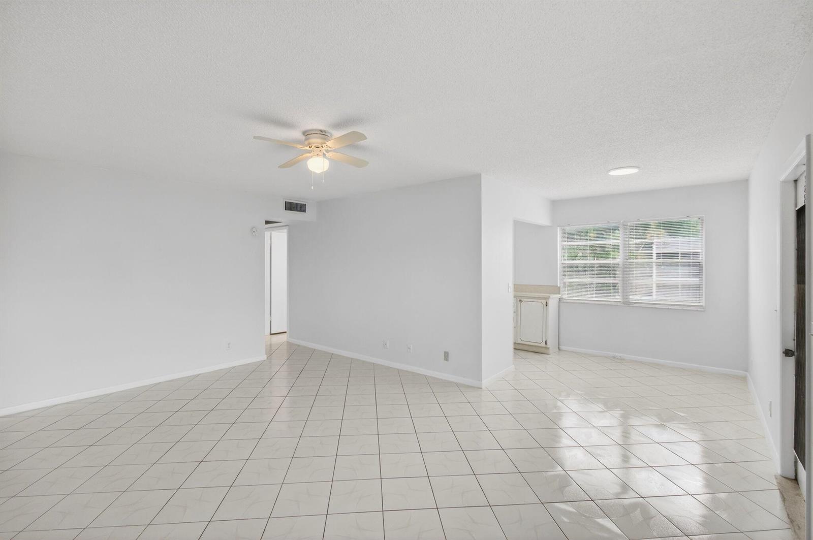 An open-concept living area features white walls, light-colored tile flooring, and a ceiling fan — 360 Fanshaw I, Boca Raton FL 33434, BOCA RATON, FL