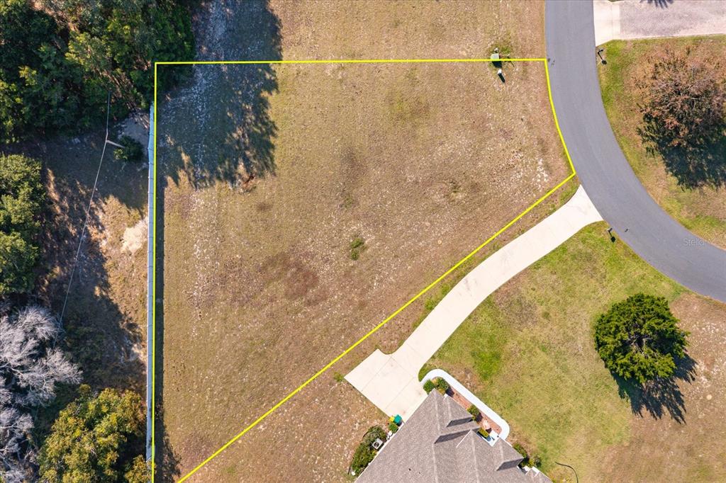 An aerial view shows a vacant, irregularly shaped residential lot adjacent to a paved driveway — 1005 MYRTLE BREEZES COURT, FRUITLAND PARK, FL