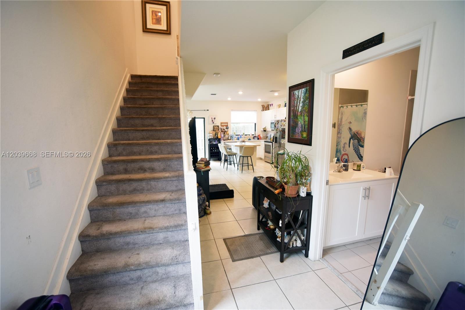 A view from a hallway showing carpeted stairs, a tiled floor, and an open kitchen — 21404 NE 3rd Path # 0, Miami FL 33179, MIAMI, FL
