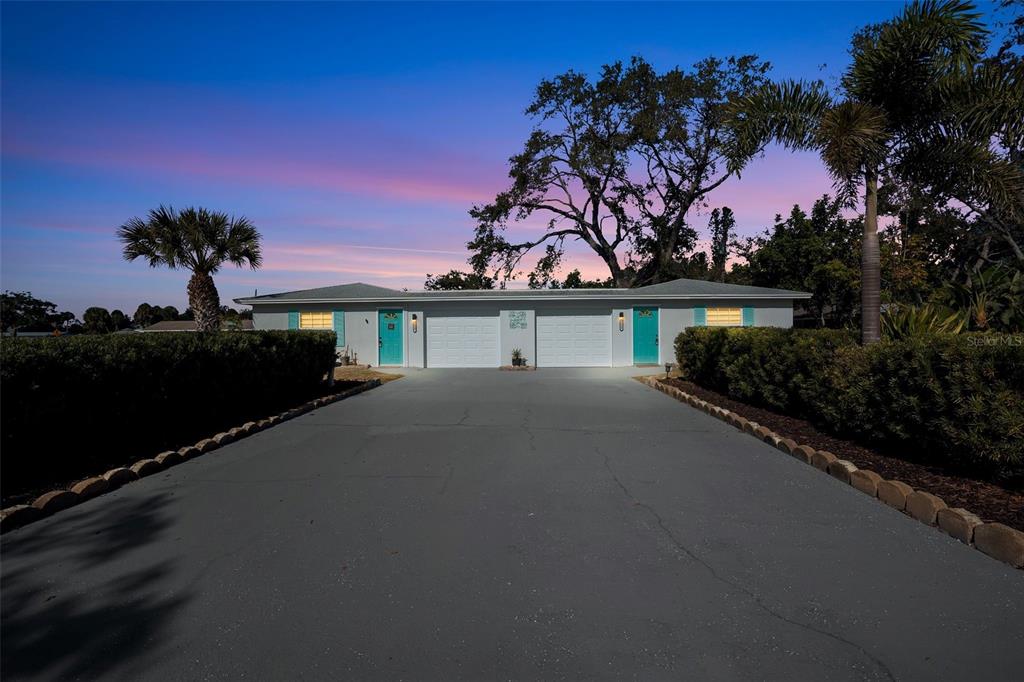 A single-story duplex with two garages and teal front doors sits at dusk — 2227-2229 MONTCLAIR DRIVE UNIT 1&2, SARASOTA, FL