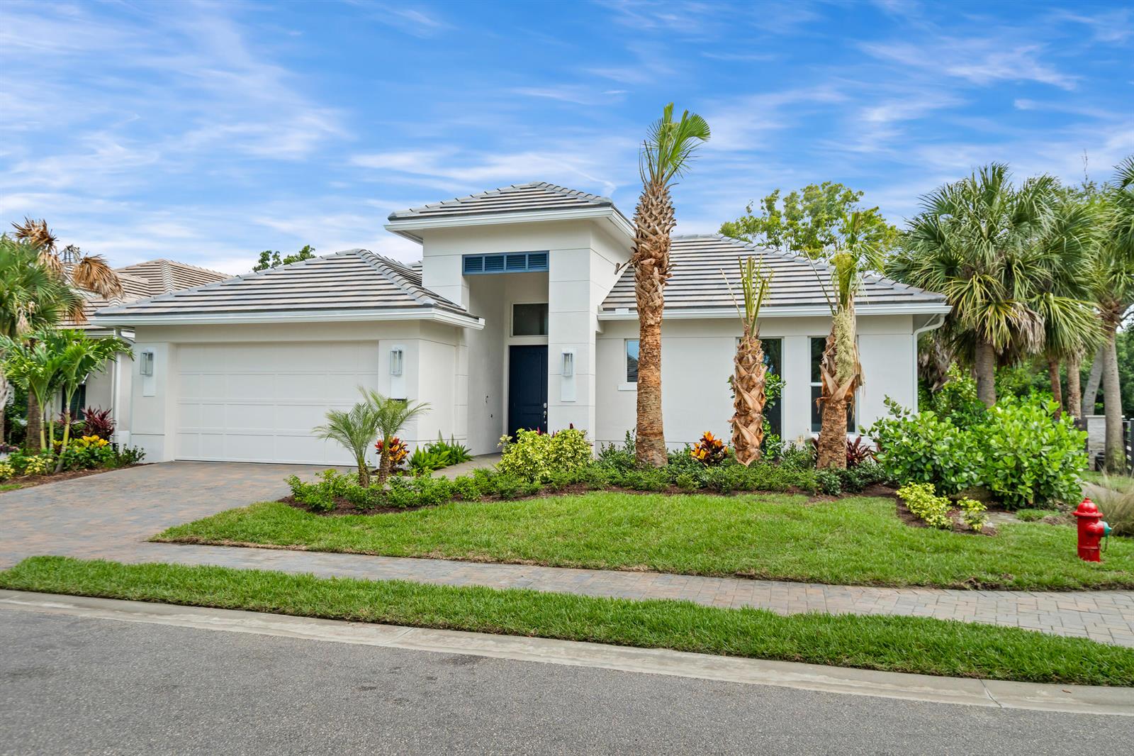 A single-story white house with a tiled roof, a two-car garage, and palm trees — 4133 Lucaya Pointe Way, Vero Beach FL 32967, VERO BEACH, FL