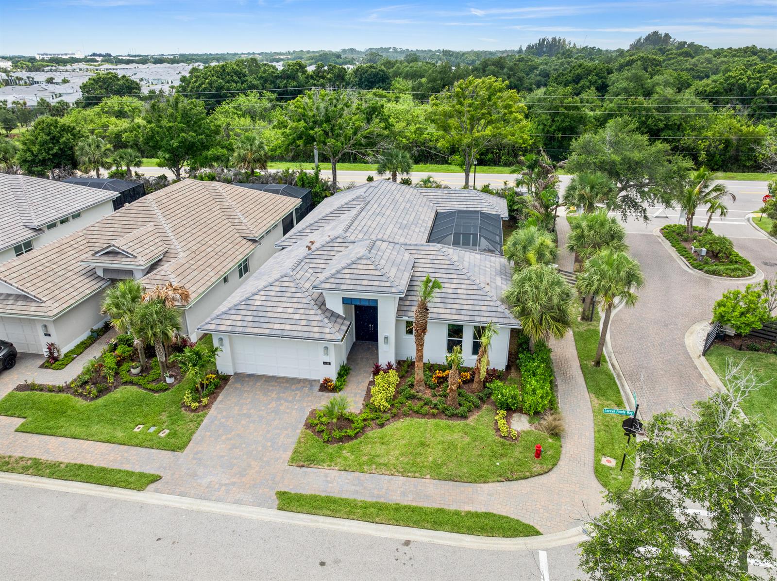 An aerial view shows a single-story house with a tiled roof, paver driveway, and landscaping — 4133 Lucaya Pointe Way, Vero Beach FL 32967, VERO BEACH, FL