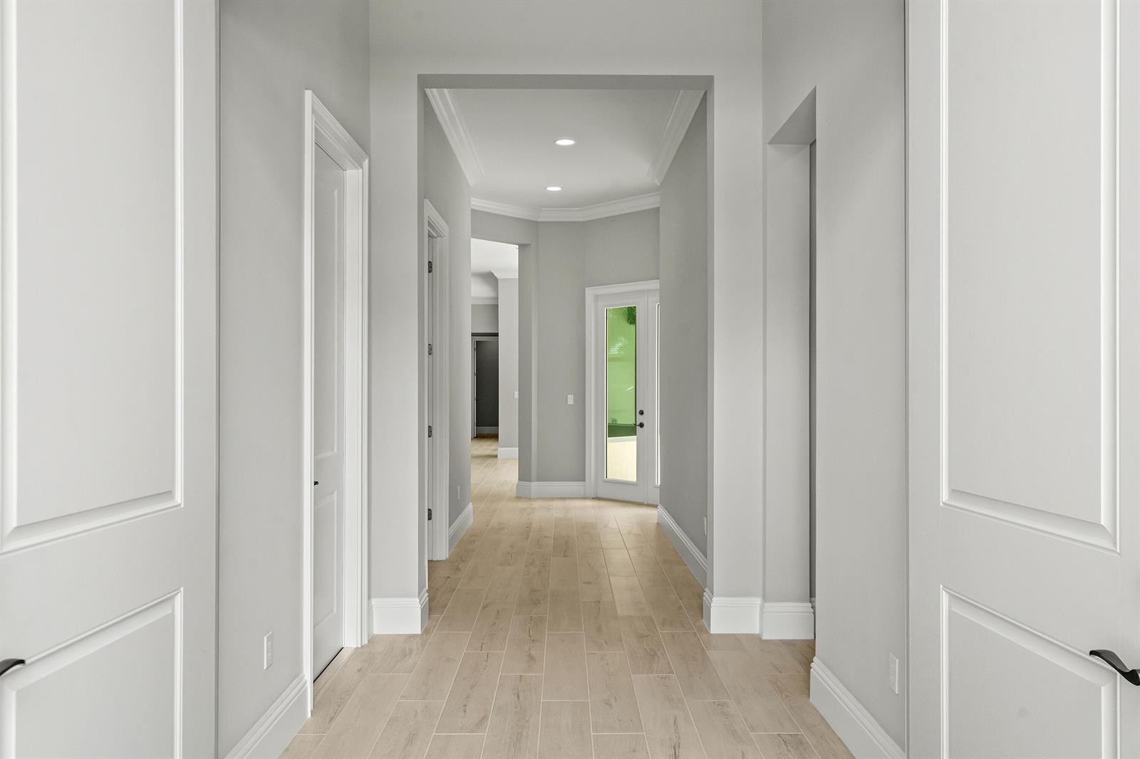 A bright hallway features light wood-look tile flooring, white walls, and several interior doors — 4133 Lucaya Pointe Way, Vero Beach FL 32967, VERO BEACH, FL