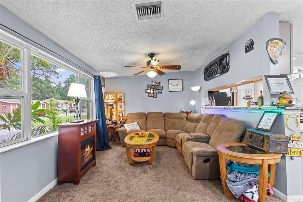 An open-concept living room and kitchen area with carpeted flooring, tile entry, and light cabinetry — 1807 CARLTON DRIVE, CLEARWATER, FL