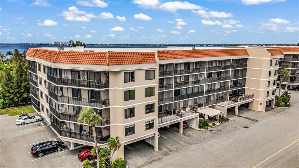 An exterior view of a multi-story apartment building with balconies and a parking lot — 25188 MARION AVENUE UNIT E212, PUNTA GORDA, FL