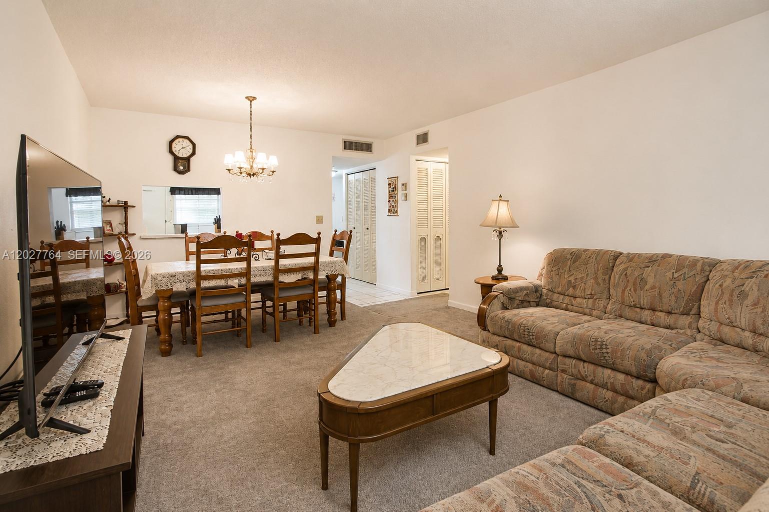 A living room and dining area feature carpeted floors, a patterned sectional sofa, and furniture — 3050 Holiday Springs Blvd # 305, Margate FL 33063, MARGATE, FL
