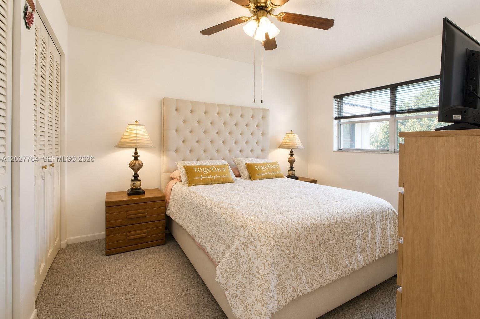 A bedroom features a tufted headboard, two wooden nightstands with lamps, and a ceiling fan — 3050 Holiday Springs Blvd # 305, Margate FL 33063, MARGATE, FL