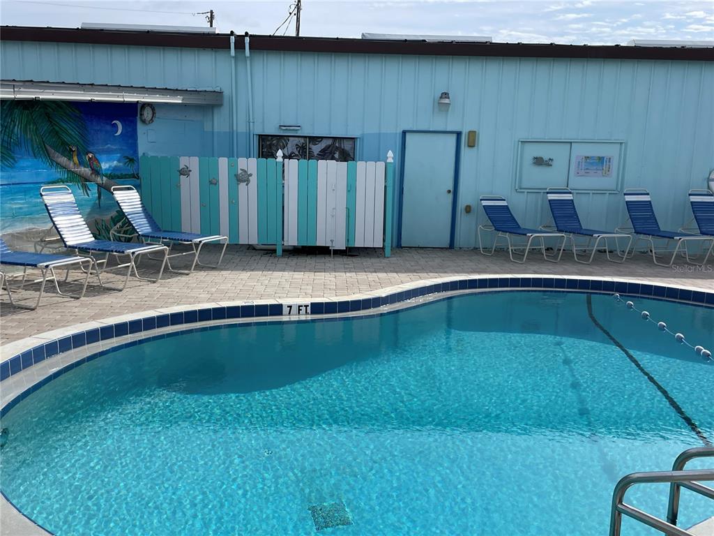 A swimming pool with a seven-foot depth marker sits in front of a blue building — 41 ILLINOIS STREET, PALMETTO, FL