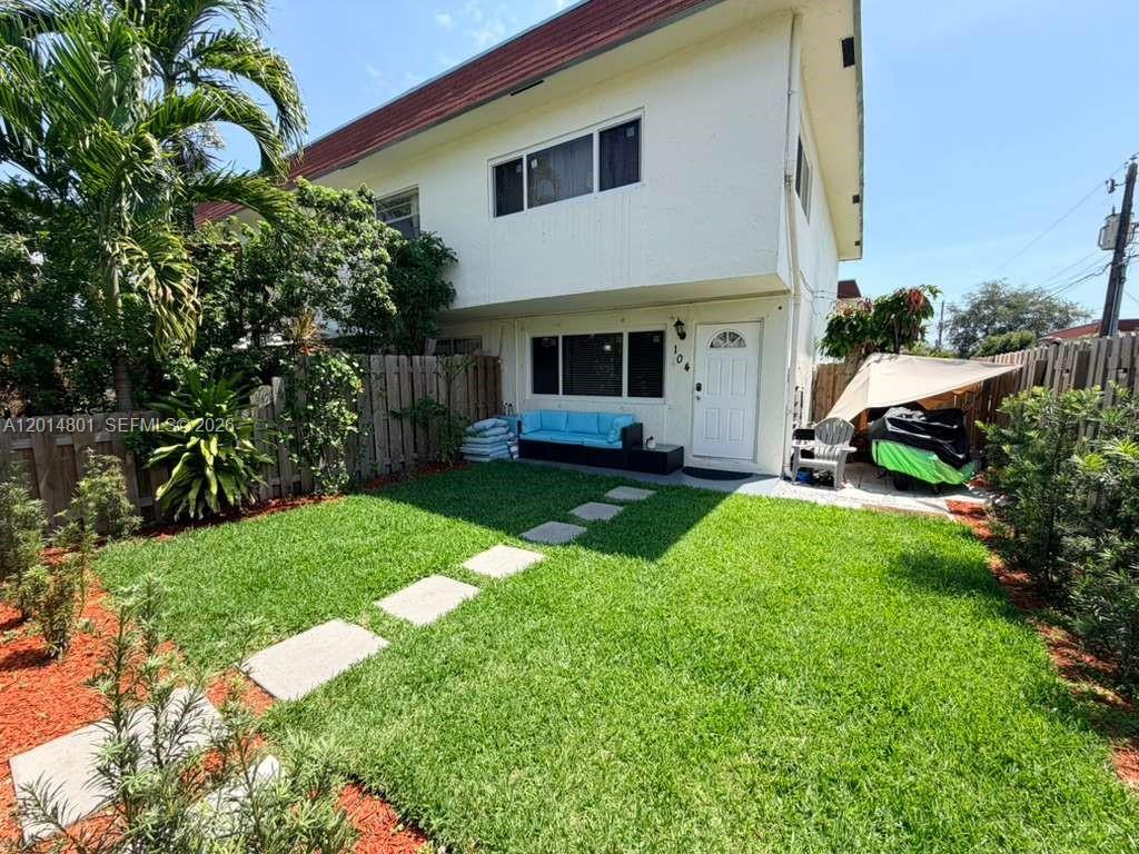 A two-story white building features a fenced backyard with a lawn and stone path — 1500 NE 151st St # 104, Miami FL 33162, MIAMI, FL