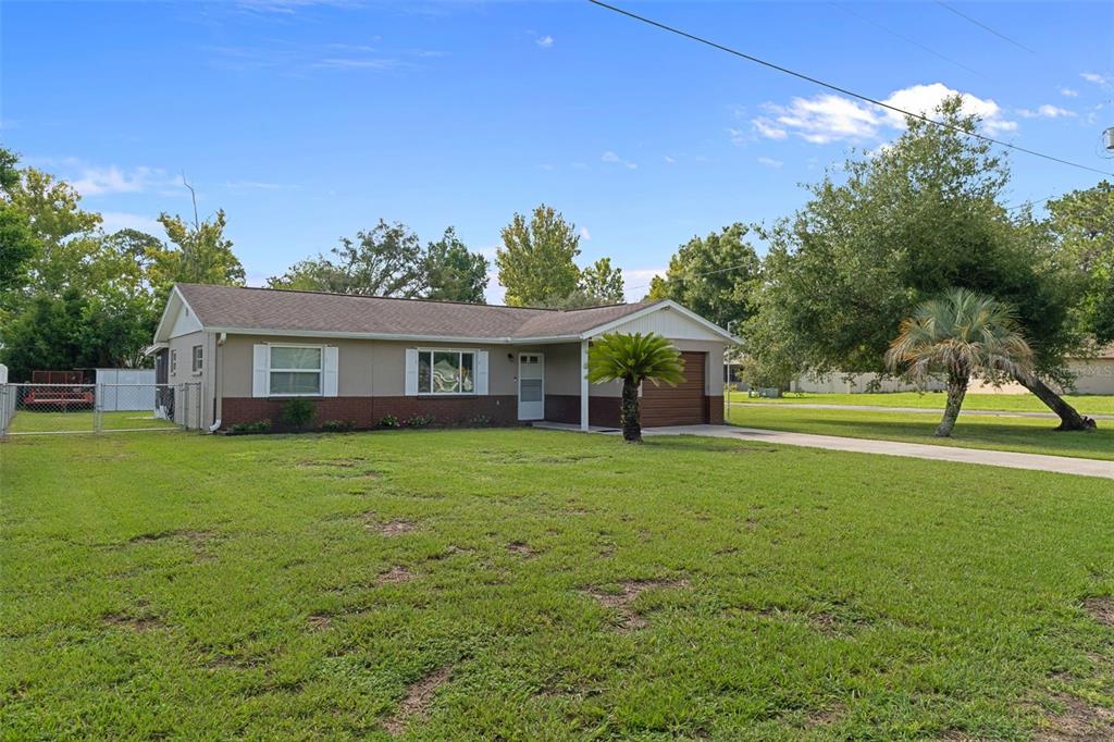 A single-story house with a brown garage and a large front lawn under blue skies — 7740 W SOLAR PLACE, HOMOSASSA, FL