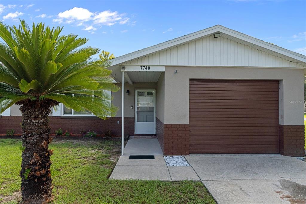 A single-story house features a brown brick lower facade, a garage, and a palm tree — 7740 W SOLAR PLACE, HOMOSASSA, FL