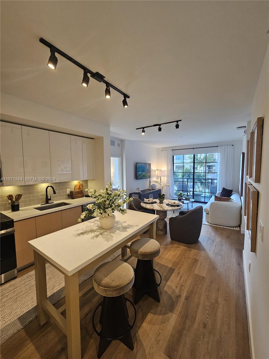 A kitchen with a white island and stools opens into a living area with balcony access — 1650 NE 124th St # 701, North Miami FL 33181, NORTH MIAMI, FL