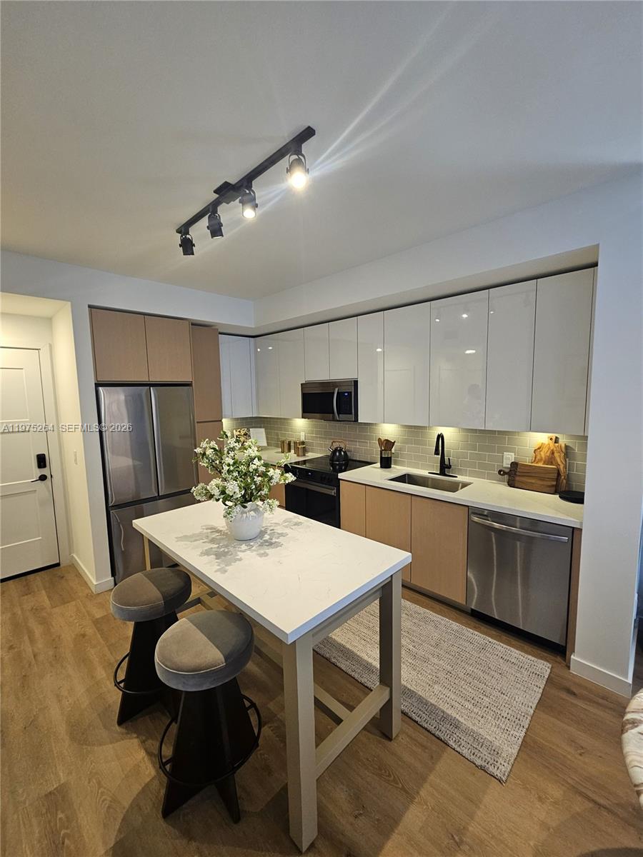 A modern kitchen features two-tone cabinetry, stainless steel appliances, and a central island with stools — 1650 NE 124th St # 701, North Miami FL 33181, NORTH MIAMI, FL