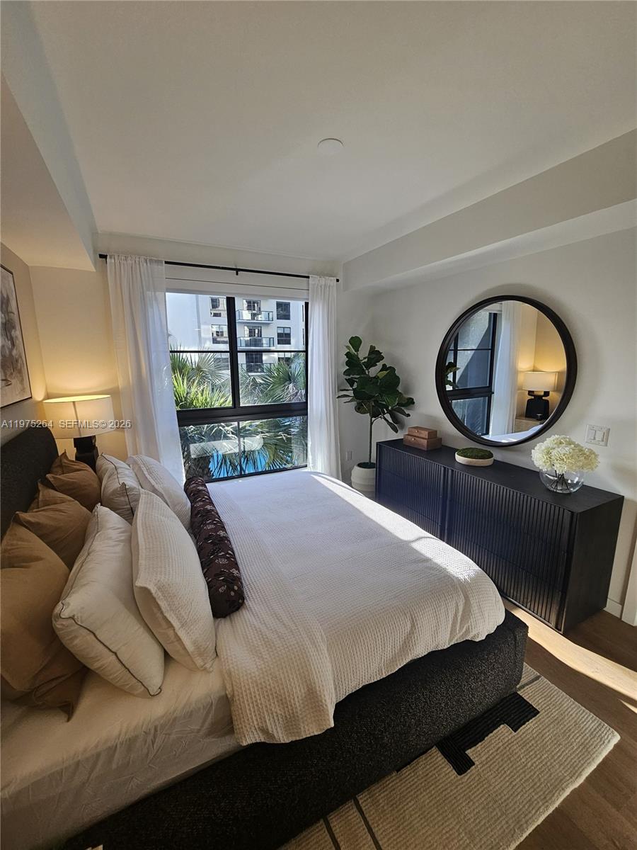 A bedroom features a dark bed, a black dresser with a round mirror, and a window — 1650 NE 124th St # 701, North Miami FL 33181, NORTH MIAMI, FL