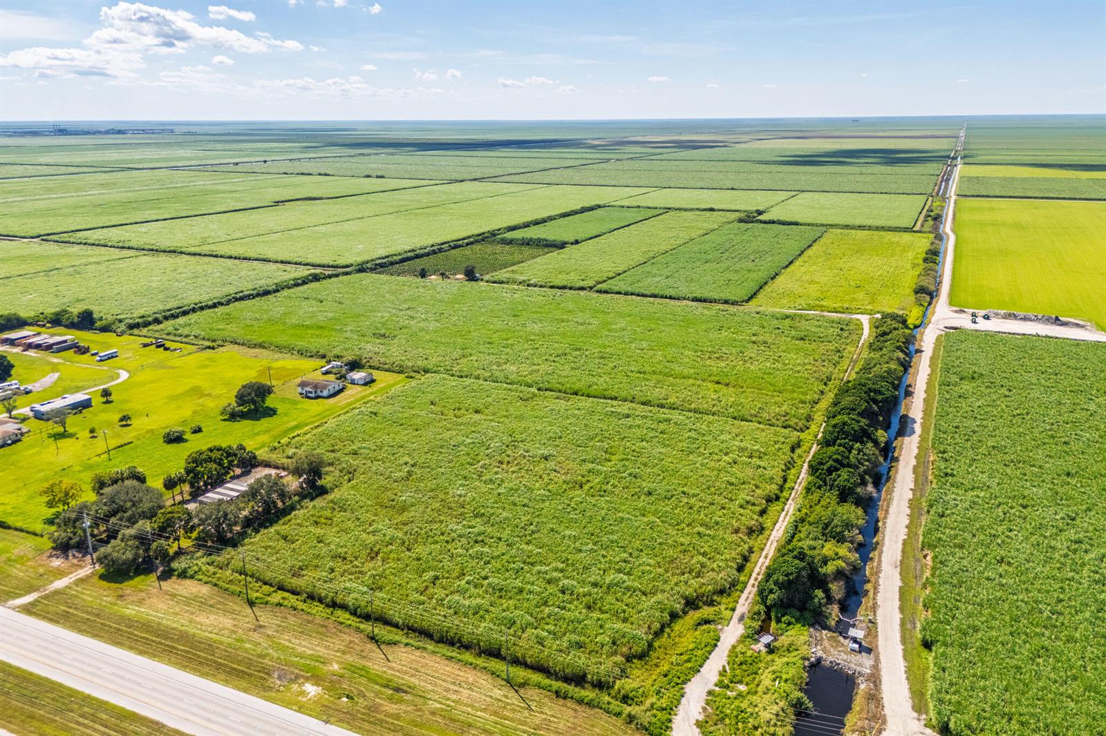 An aerial view shows a large agricultural field with a house and trees nearby — 0 Highway 27, South Bay FL 33493, SOUTH BAY, FL
