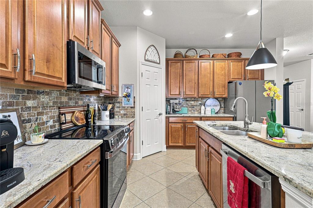 A kitchen features wood cabinets, granite countertops, stainless steel appliances, and a central island — 8478 NANDINA DRIVE, SARASOTA, FL