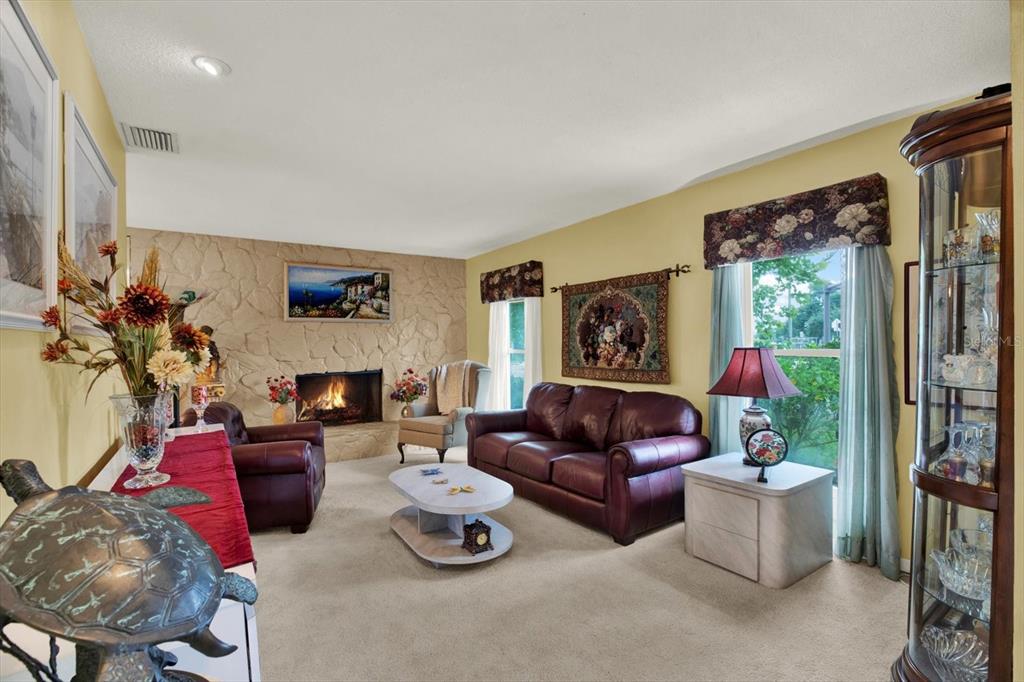 A living room features a stone fireplace, leather furniture, and a glass display cabinet — 5790 150TH AVENUE N, CLEARWATER, FL