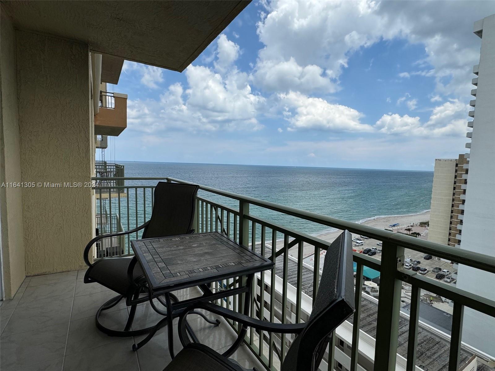 A balcony with a small table and two chairs overlooks the ocean and beach — 2080 S Ocean Dr # 1607, Hallandale Beach FL 33009, HALLANDALE BEACH, FL