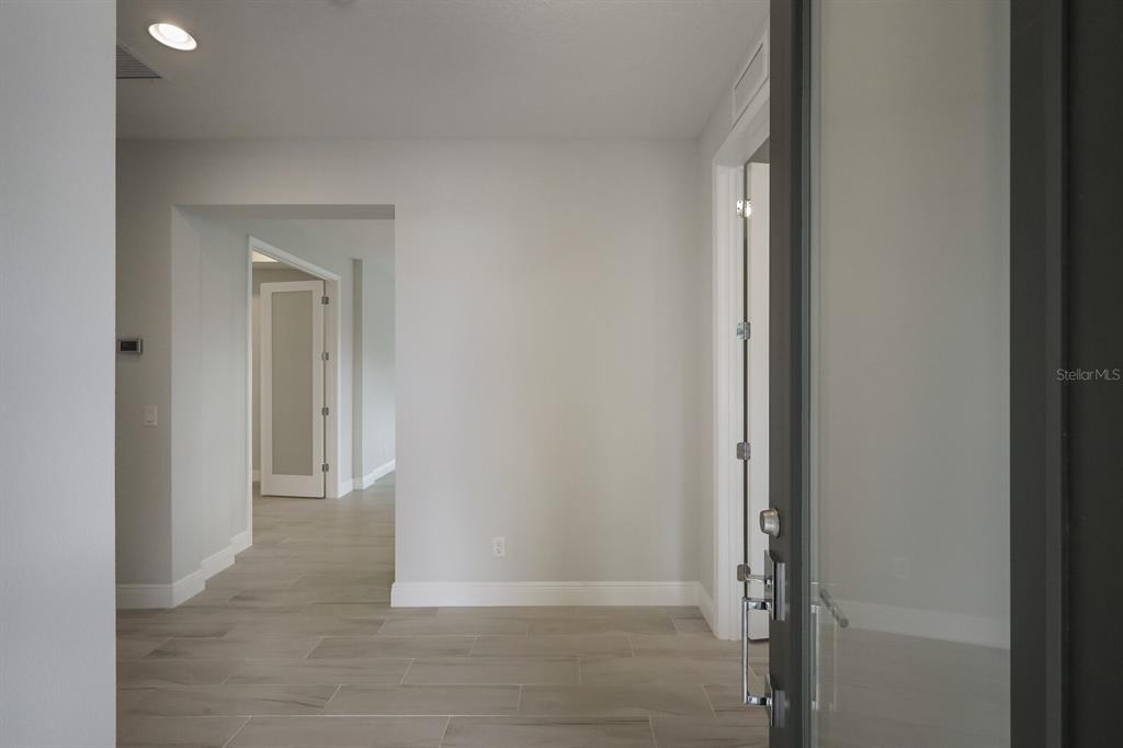 An entryway features light-colored tile flooring, white walls, and a glass-paneled front door — 10748 KLEE AVENUE, BRADENTON, FL