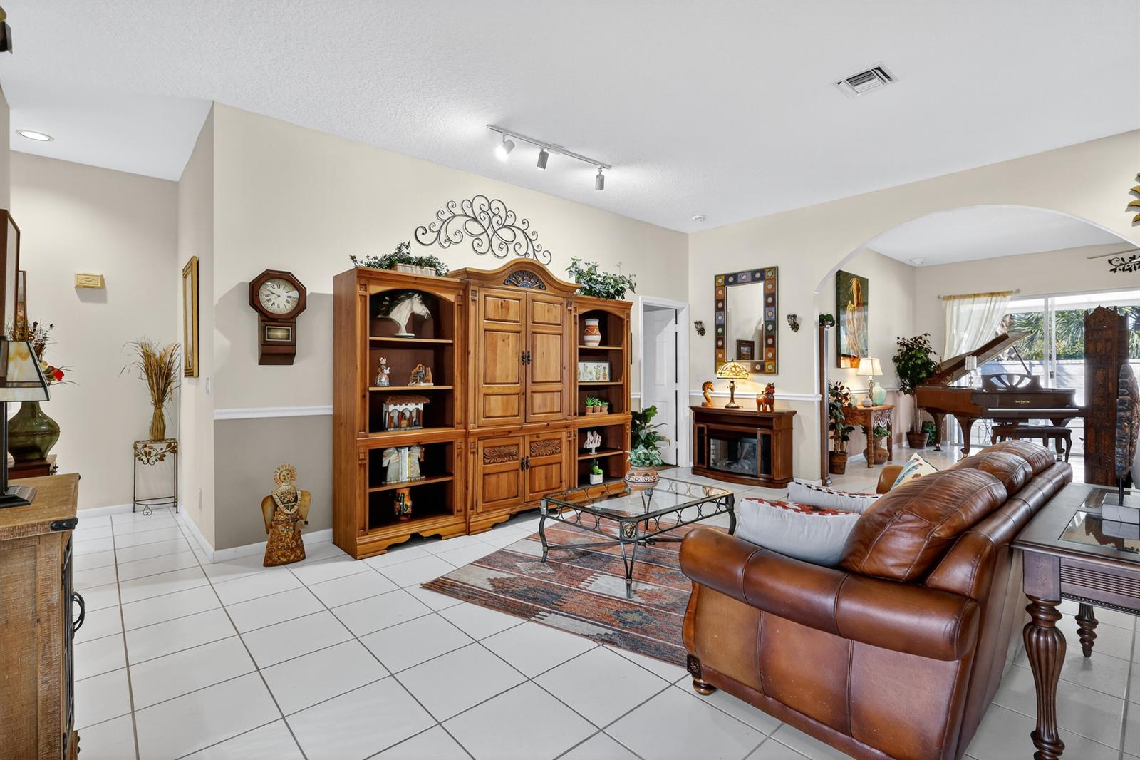 A living room features tile flooring, a large wooden entertainment center, and a leather sofa — 3747 Spring Crest Court, Lake Worth FL 33467, LAKE WORTH, FL