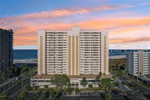 A wide sandy beach leads to several tall residential buildings under a blue sky — 1270 GULF BOULEVARD UNIT 1206, CLEARWATER BEACH, FL