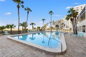 A swimming pool surrounded by lounge chairs, palm trees, and multi-story apartment buildings — 1270 GULF BOULEVARD UNIT 1206, CLEARWATER BEACH, FL