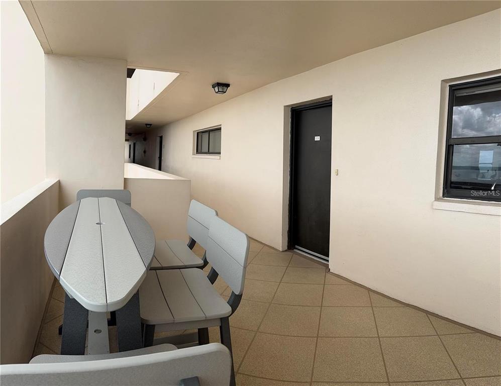 A swimming pool with lounge chairs and palm trees sits on a paved patio deck — 1270 GULF BOULEVARD UNIT 1206, CLEARWATER BEACH, FL