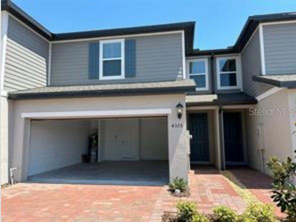 A two-story townhouse exterior with a one-car garage and a brick paver driveway — 4325 EAGLE TRAIL BEND, ST CLOUD, FL