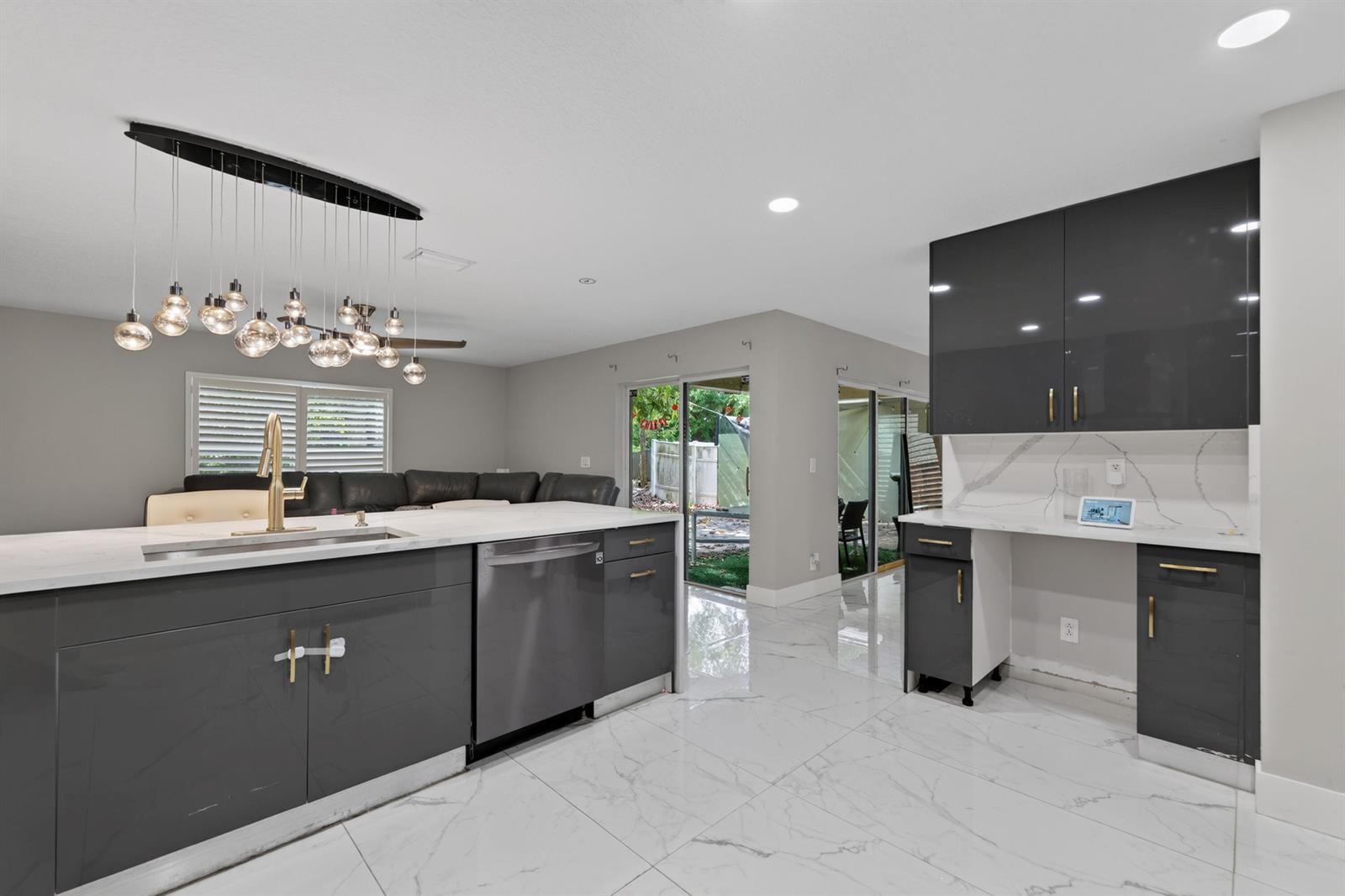 A modern kitchen features gray cabinets, white marble countertops, and a large multi-bulb pendant light — 6544 Adriatic Way, FL 33413, FL