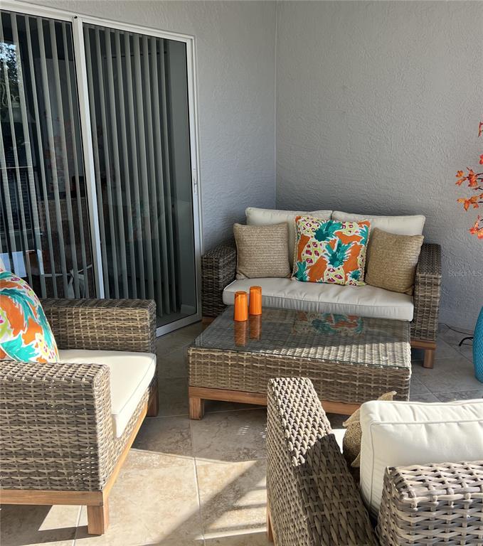 A patio features wicker furniture with white cushions and a glass-topped coffee table — 4639 CHAPEL HILL DRIVE UNIT 2923, SARASOTA, FL