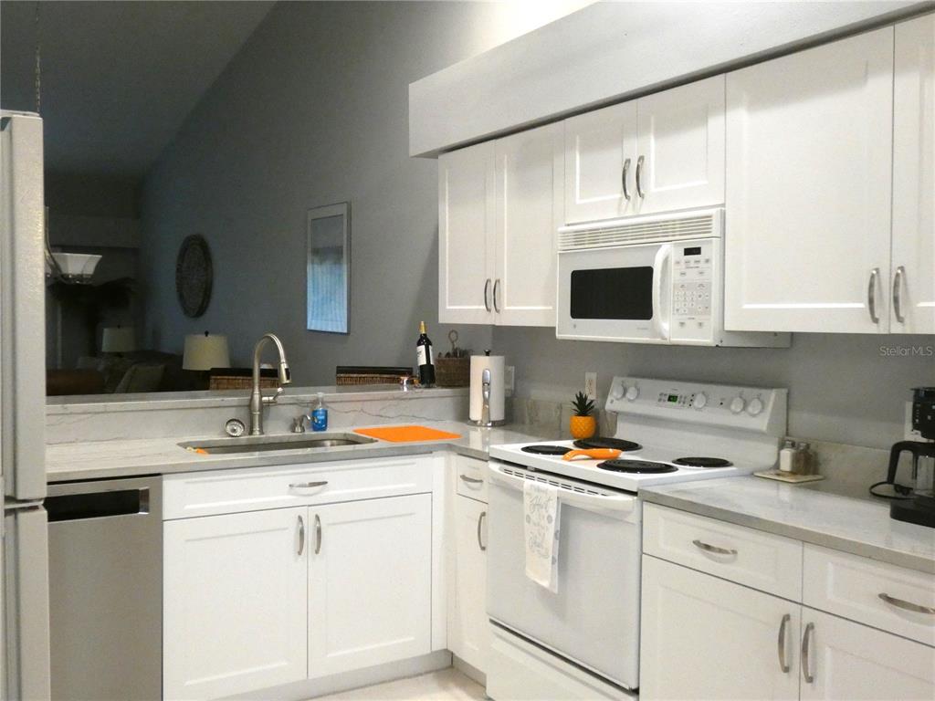 A kitchen features white cabinets, stainless steel appliances, and light-colored countertops — 4639 CHAPEL HILL DRIVE UNIT 2923, SARASOTA, FL