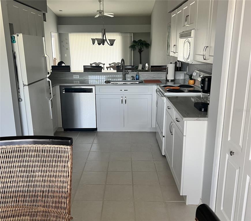 A kitchen features white cabinets, stainless steel appliances, and light tile flooring — 4639 CHAPEL HILL DRIVE UNIT 2923, SARASOTA, FL