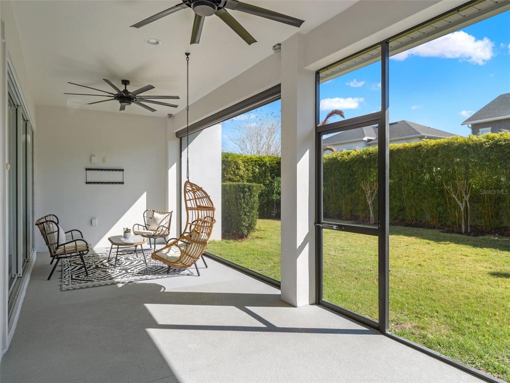 A covered patio features a concrete floor, two ceiling fans, and a hanging wicker chair — 12515 BOVET AVENUE, ORLANDO, FL