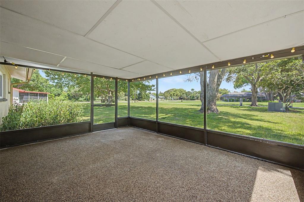 A screened-in porch with a textured concrete floor and views of a grassy yard — 7800 FAIRLAWN DRIVE, HUDSON, FL