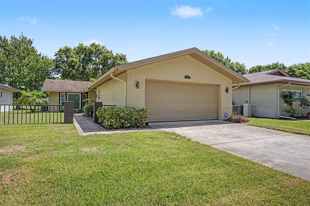 A single-story house with a beige stucco exterior, a two-car garage, and a front lawn — 7800 FAIRLAWN DRIVE, HUDSON, FL