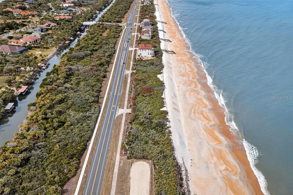 An aerial view shows a coastal road separating a residential area from the sandy beach — 3709 N OCEAN SHORE BOULEVARD, PALM COAST, FL