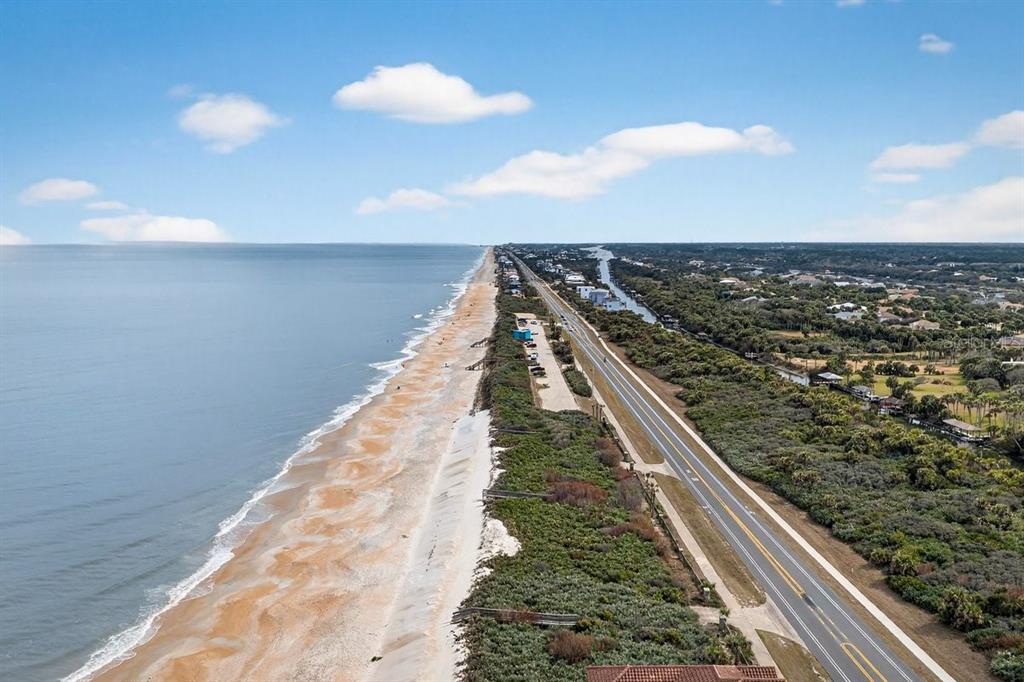 An aerial view shows a coastal road running parallel to a sandy beach and ocean — 3709 N OCEAN SHORE BOULEVARD, PALM COAST, FL