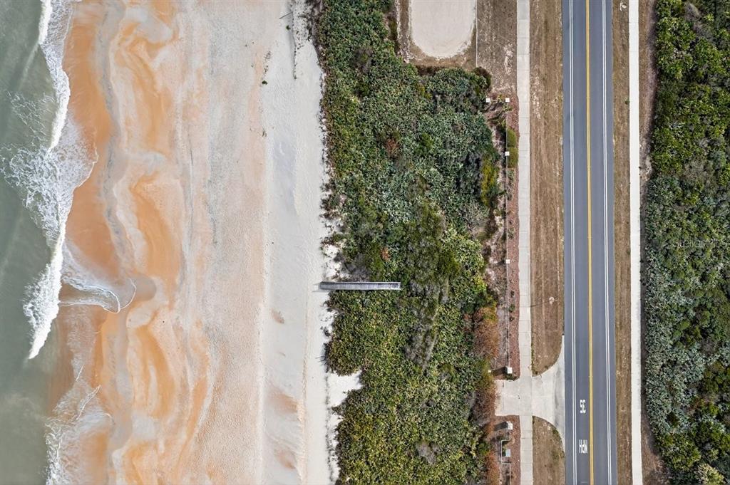 An aerial view shows a beach, a wooden boardwalk, dense vegetation, and a paved road — 3709 N OCEAN SHORE BOULEVARD, PALM COAST, FL