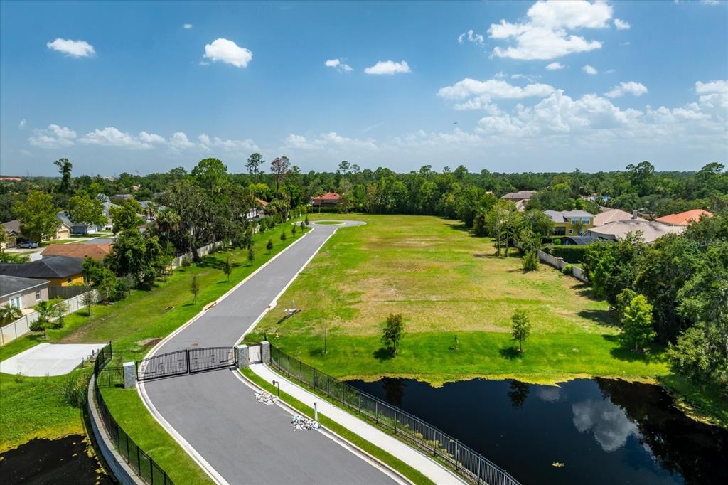 An aerial view shows a gated road leading to a large, vacant grassy lot — 950 FRIENDS COURT, SANFORD, FL
