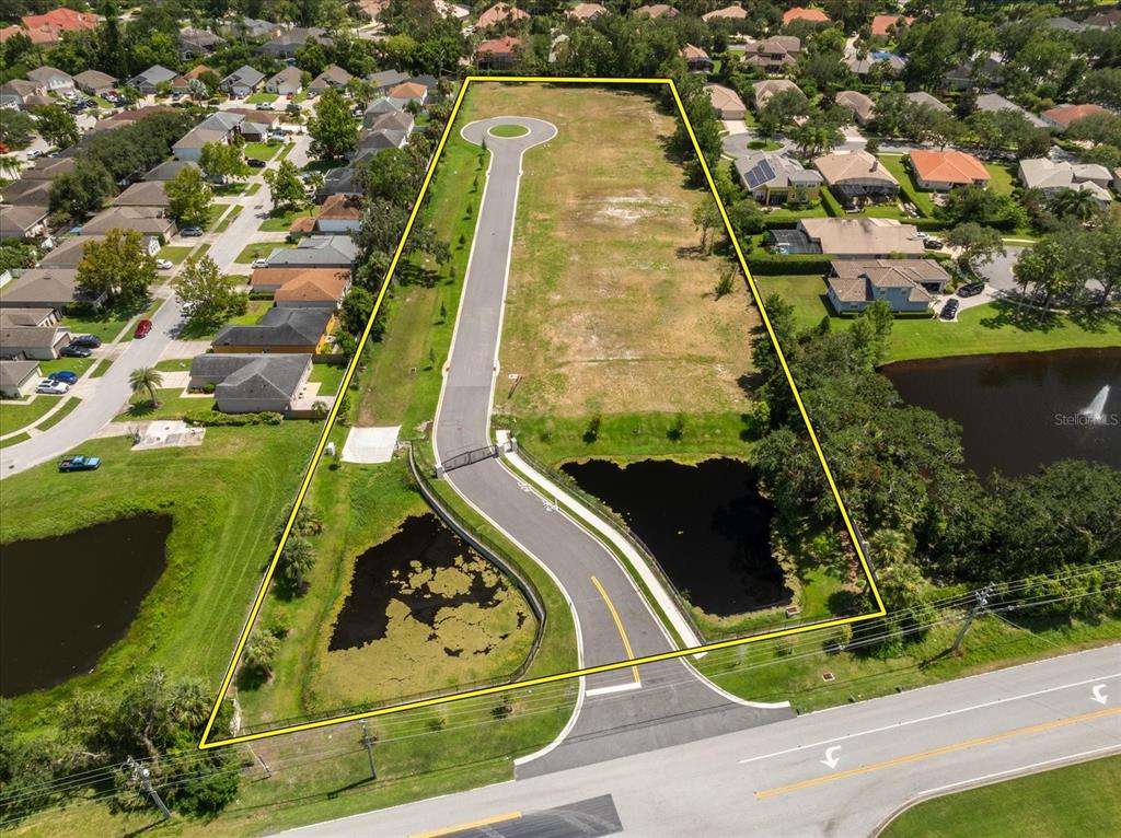 An aerial view shows a vacant, gated residential lot with a paved road and ponds — 950 FRIENDS COURT, SANFORD, FL