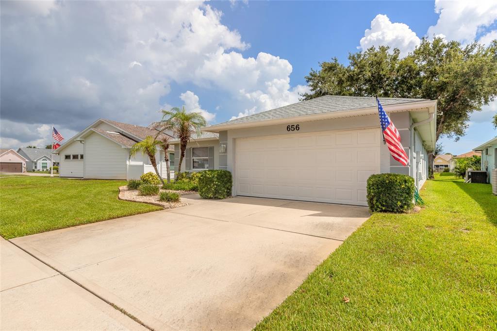 A single-story house with a two-car garage, a concrete driveway, and an American flag — 656 MIDDLEBURY LOOP, NEW SMYRNA BEACH, FL