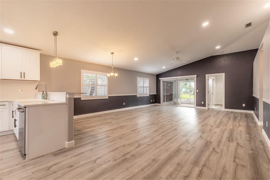 An open-concept kitchen and living area features light wood flooring and two-toned gray walls — 656 MIDDLEBURY LOOP, NEW SMYRNA BEACH, FL