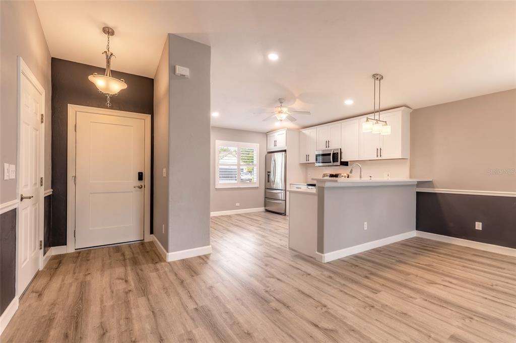 A bright kitchen and entryway feature white cabinets, stainless steel appliances, and light wood flooring — 656 MIDDLEBURY LOOP, NEW SMYRNA BEACH, FL