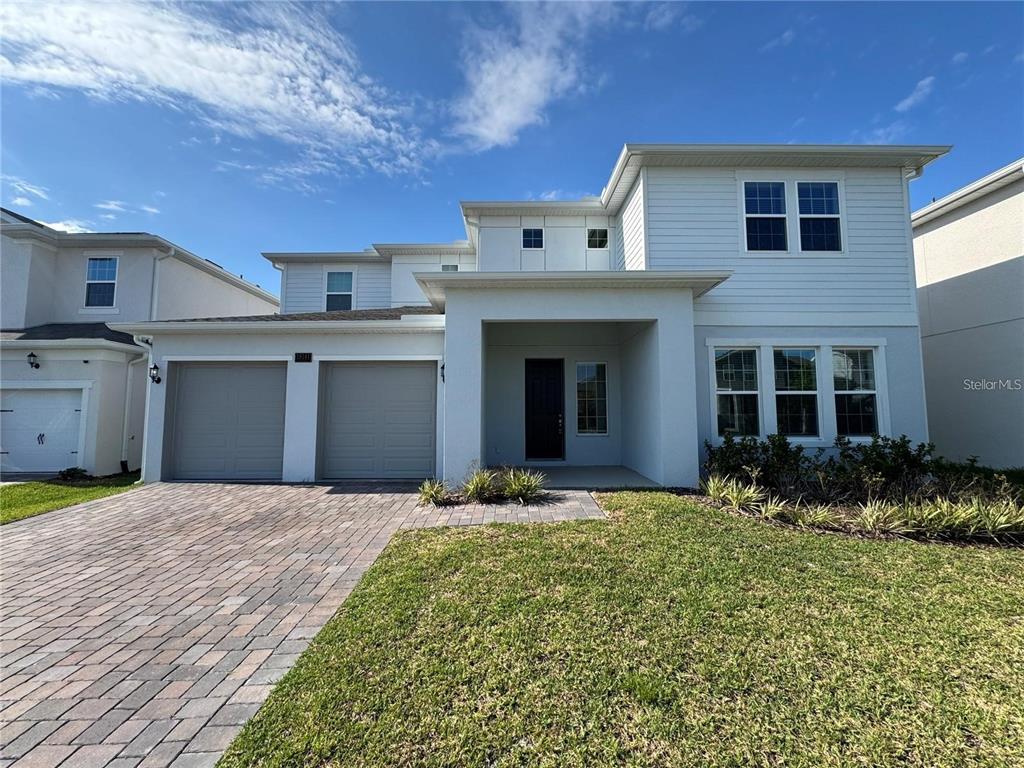 A two-story house with a two-car garage, light siding, and a paved driveway — 19141 PLANETREE STREET, ORLANDO, FL