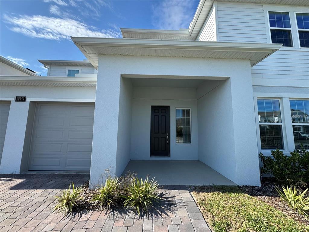 A white two-story house exterior features a covered entryway, a dark front door, and garage — 19141 PLANETREE STREET, ORLANDO, FL