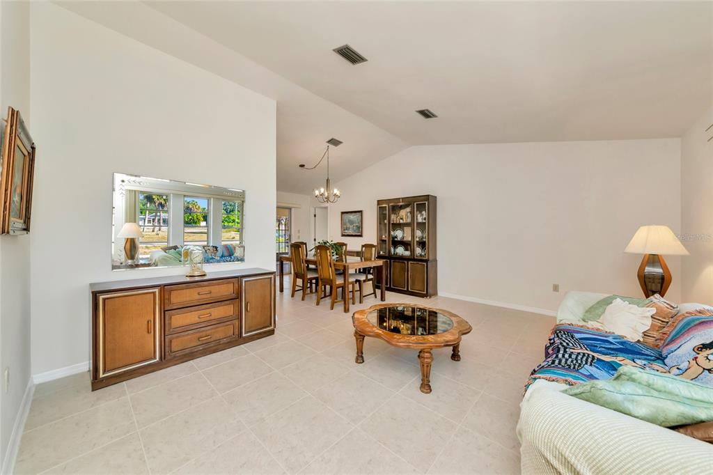 A living and dining area with tile floors, vaulted ceilings, and traditional wood furniture — 2176 BARKSDALE STREET, PORT CHARLOTTE, FL