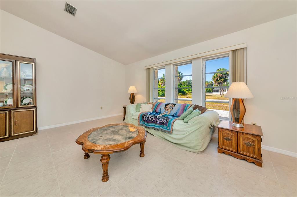 A living room features tile flooring, a beige sofa, a coffee table, and large windows — 2176 BARKSDALE STREET, PORT CHARLOTTE, FL