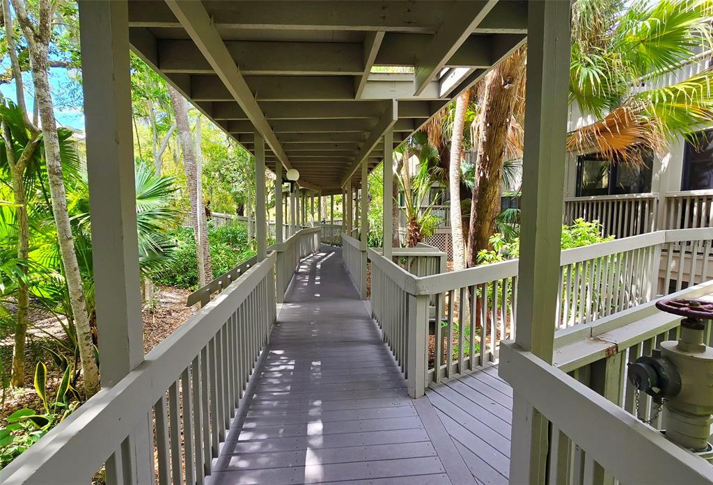 A covered wooden walkway with railings leads through a lush, tropical outdoor area — 1335 LANDINGS DRIVE UNIT 9, SARASOTA, FL