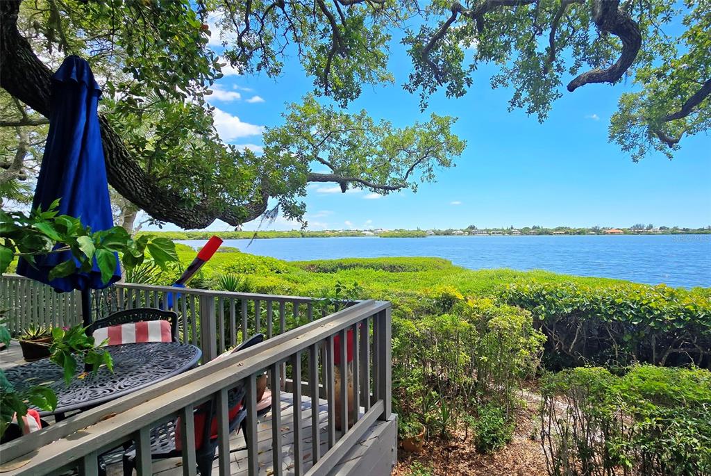 A wooden deck with a patio table and blue umbrella overlooks a bay and mangroves — 1335 LANDINGS DRIVE UNIT 9, SARASOTA, FL