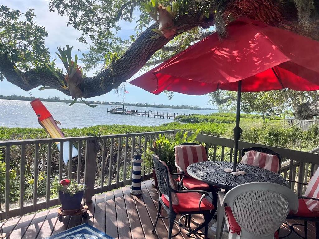 A wooden deck features a patio table with a red umbrella overlooking a waterfront view — 1335 LANDINGS DRIVE UNIT 9, SARASOTA, FL